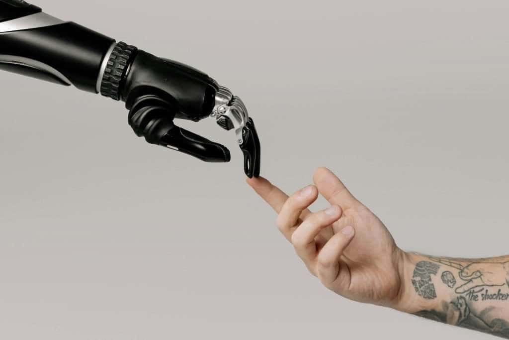 Human and robotic hands reaching toward each other, symbolizing collaboration with AI agents in the future workplace